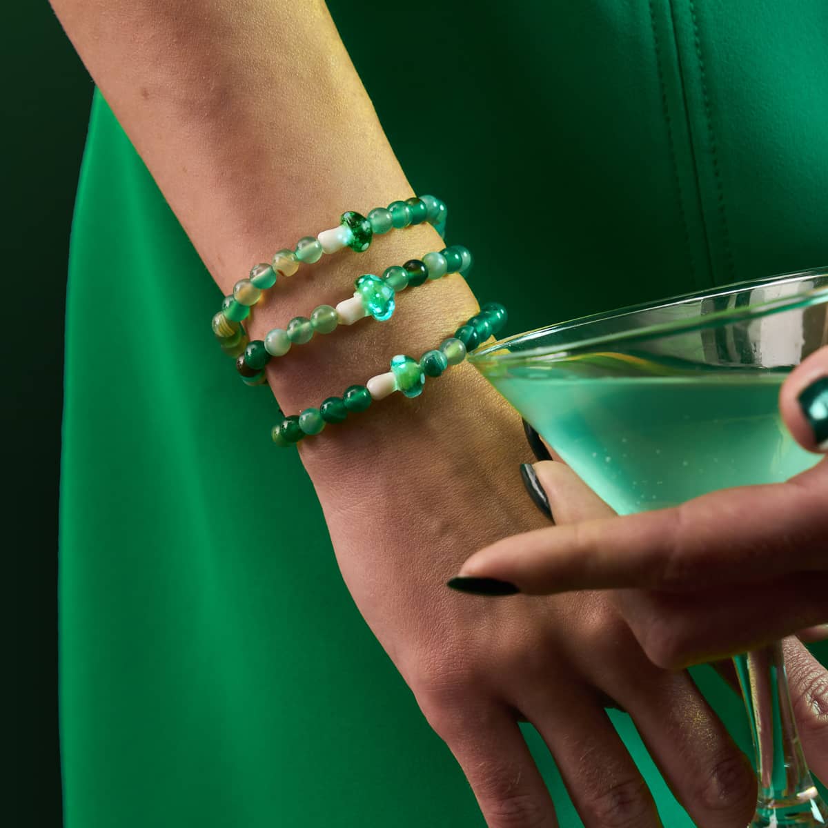 Green Agate bracelets with 4mm beads and glowing Firefly Glass mushroom accents worn on wrist by model in green outfit by NOGU